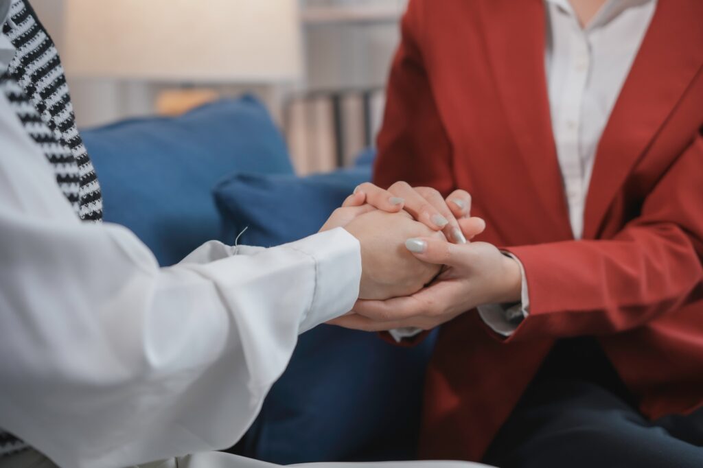 Psychologist holding hands of patient during therapy session